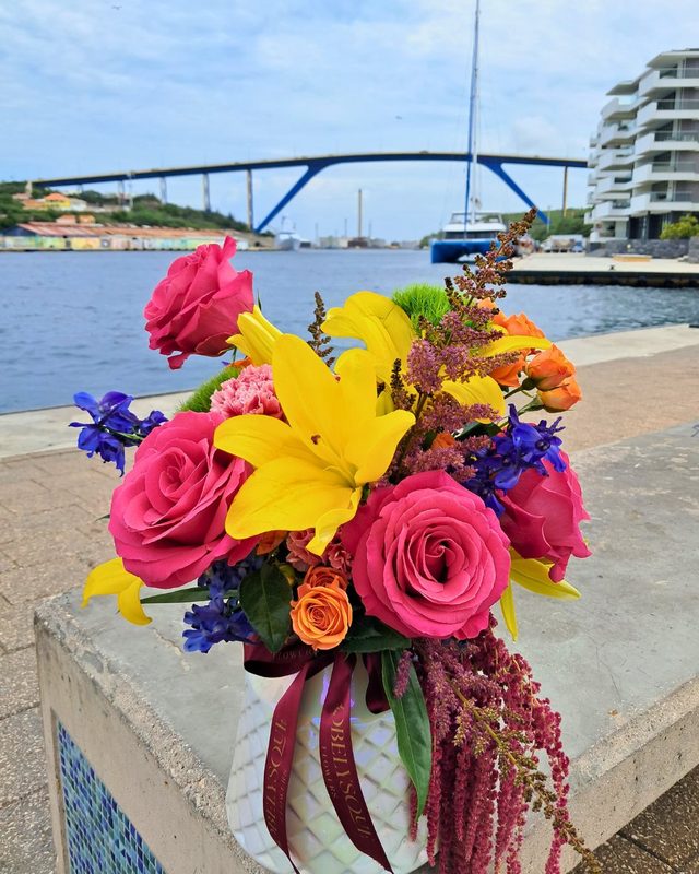 A bright bouquet of roses and lilies in front of the Queen Juliana Bridge